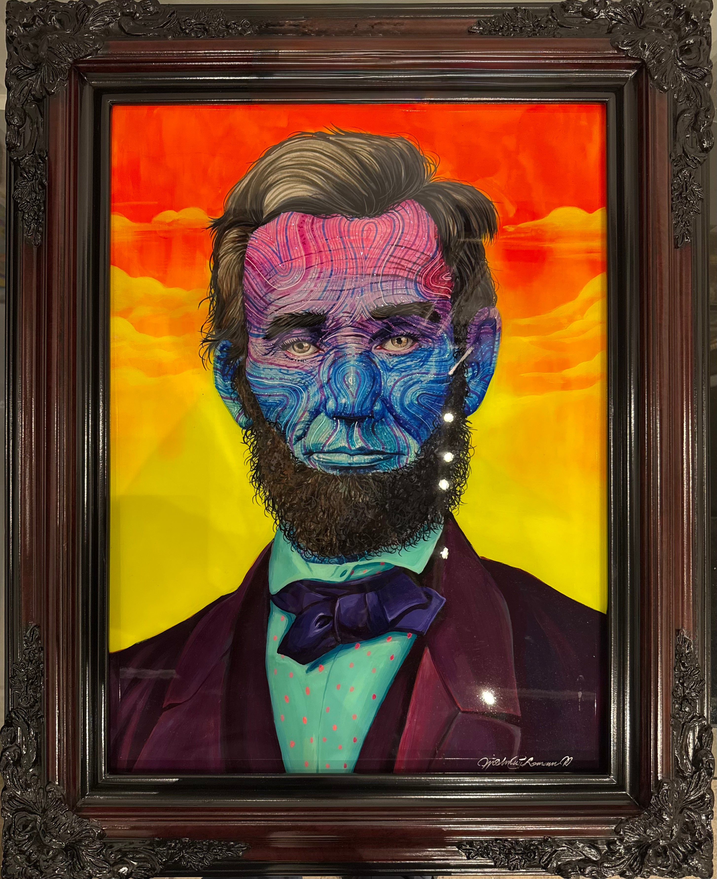 A framed portrait painting of Abraham Lincoln with a vibrant, colorful background. The portrait features a dark brown ornate wooden frame, with the painting itself showing Lincoln's face in shades of blue and pink, wearing a purple bow tie and dark jacket against a bright yellow and orange sky.